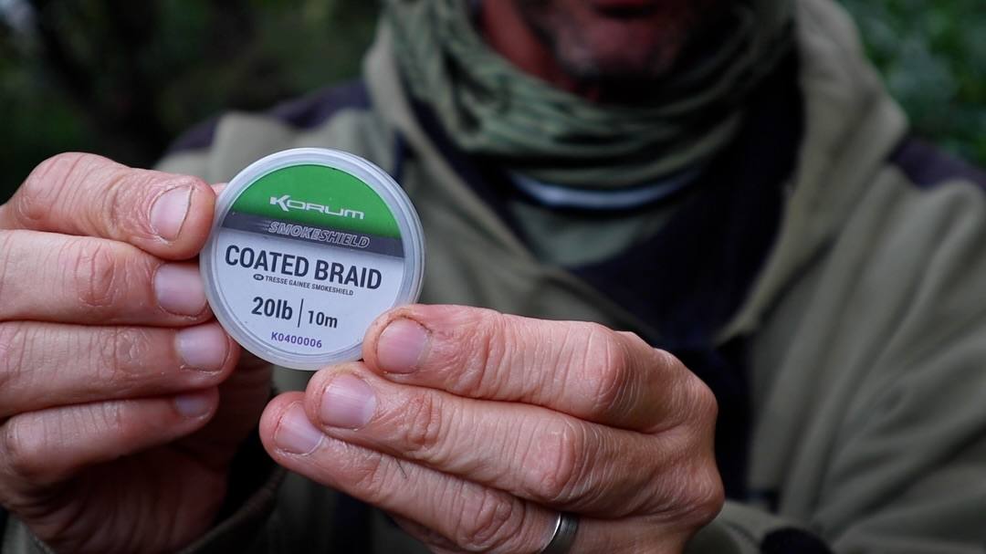 Close-up of an angler holding a spool of Korum Smoke Shield 20lb coated braid for Autumn Barbel Fishing.