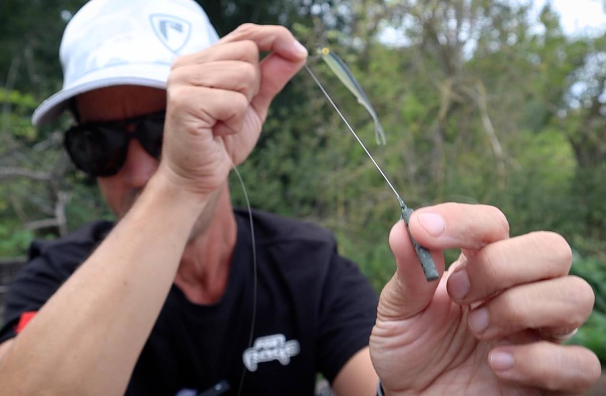 Dropshot rig with a small fish-shaped lure above a slim cylindrical weight