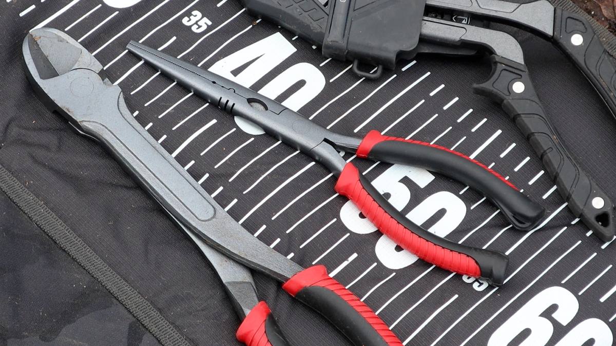 Essential pike fish care kit laid out on an unhooking mat including pliers, side cutters and wire traces